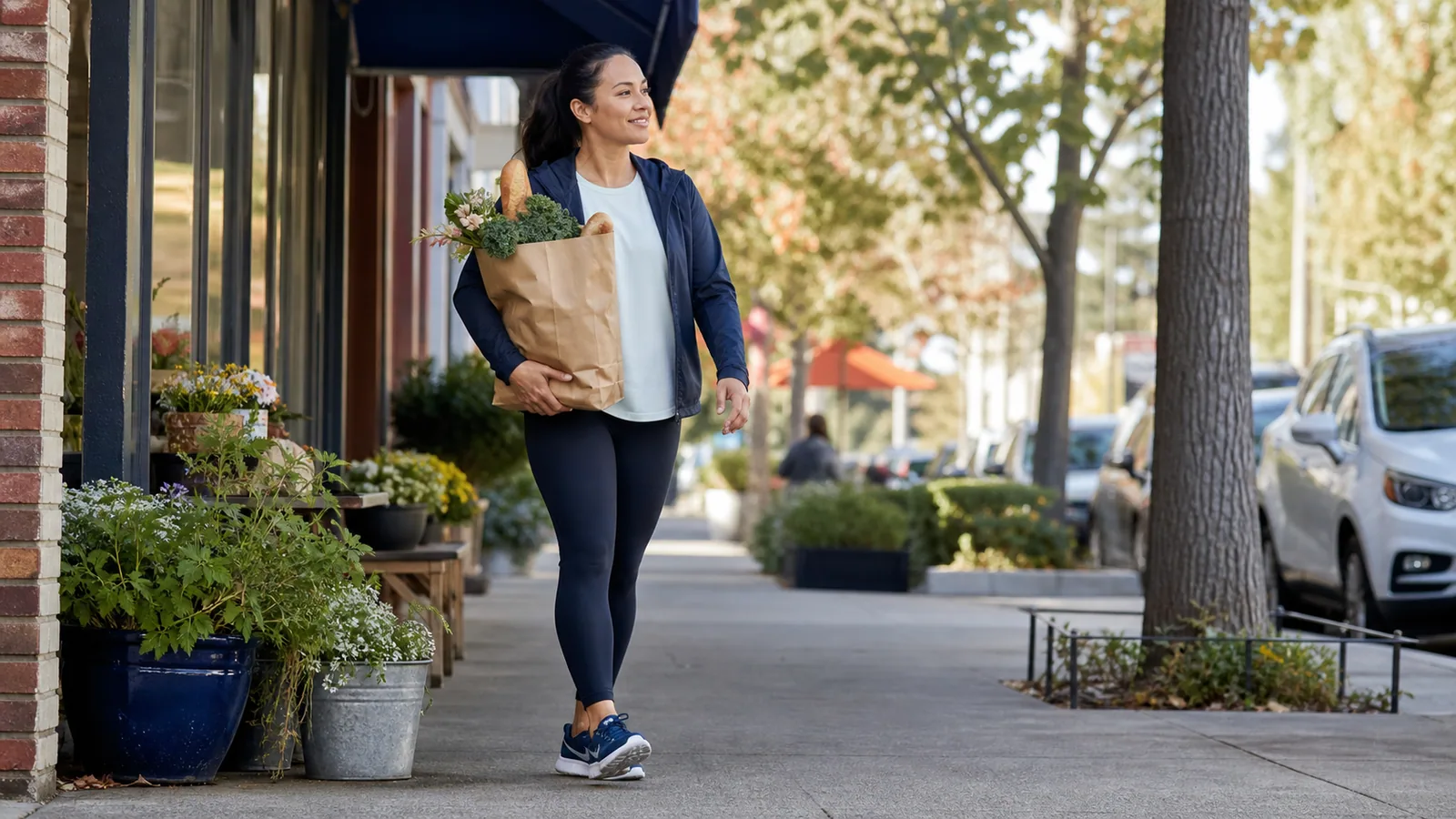 Person wearing cushioned walking shoes while carrying groceries on a neighborhood sidewalk